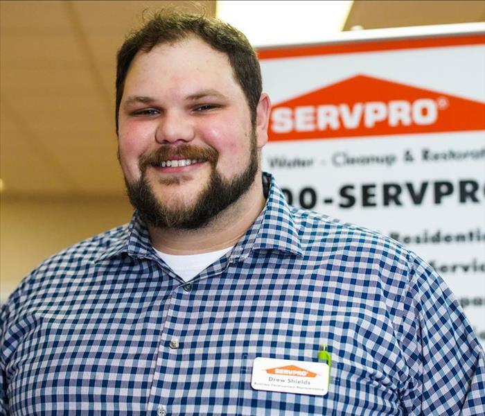 business rep in front of a SERVPRO sign in a blue and white checkered shirt